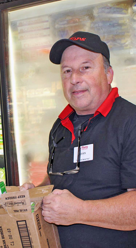 A man in a Tops Market uniform smiles at the camera