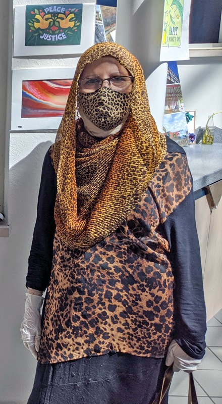 A woman wearing a cheetah print headscarf and mask