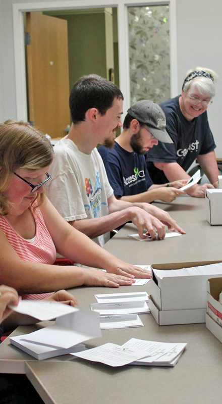 A group of 4 people are seen at a table stuffing envelopes